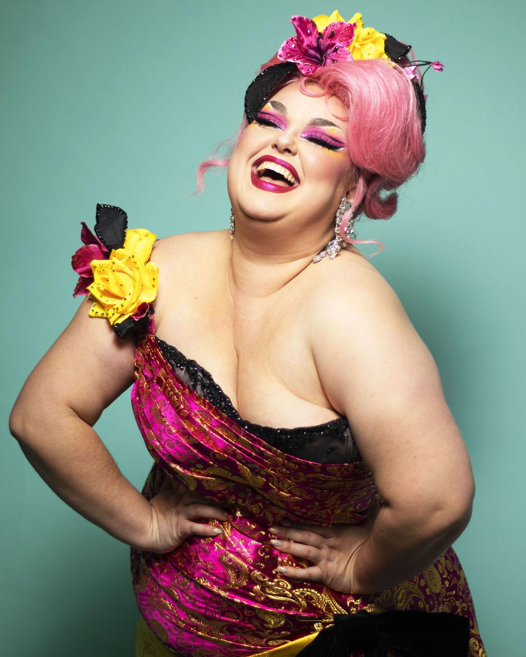 Betsy Mae laughing broadly, dressed in a pink velvet dress with a yellow rose on the shoulder