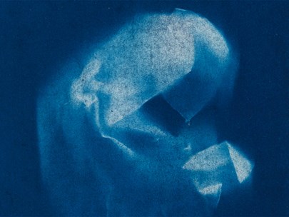 Light coloured crumpled fabric against a dark blue backdrop.