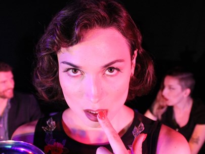 Woman in foreground with finger on her lips and people seated behind her