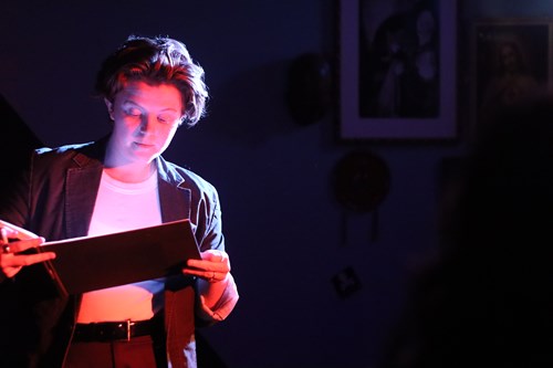 Emily is wearing a white top and dark-coloured blazer, gazing intently into a book.