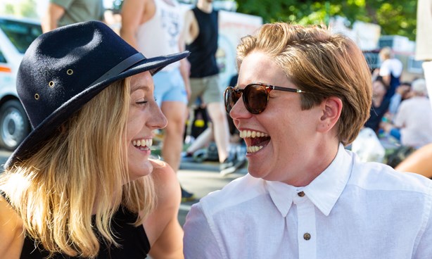Two female-identifying people looking at each other while laughing loudly