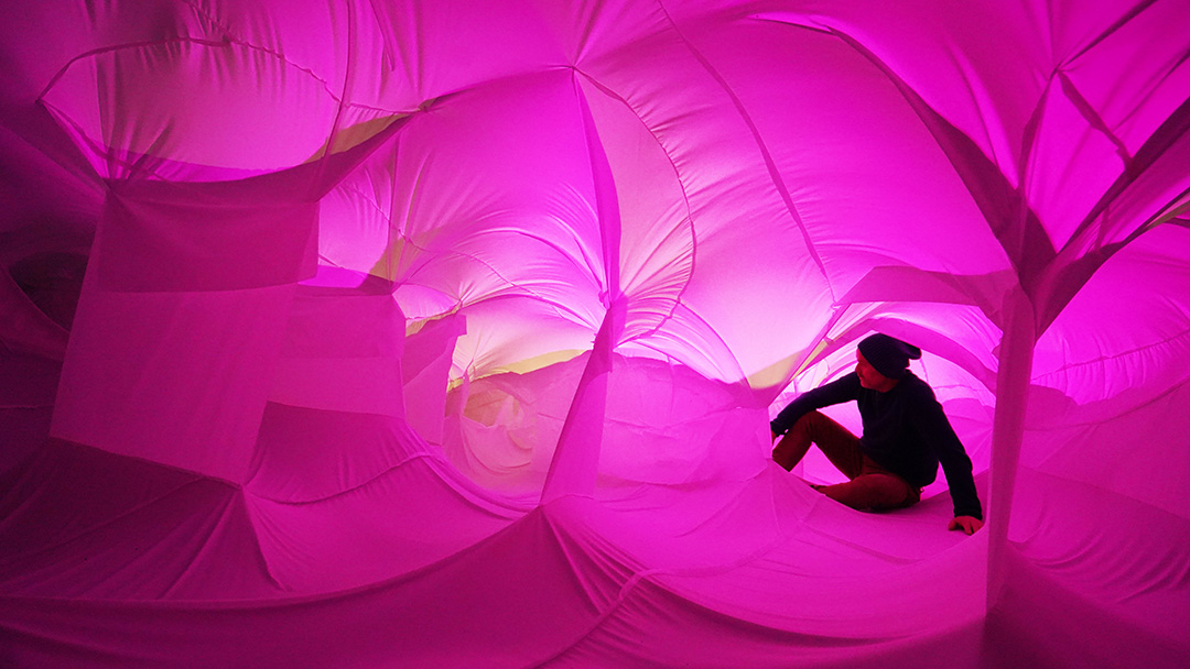Person 'lost' inside a giant, fabric pink-coloured art installation
