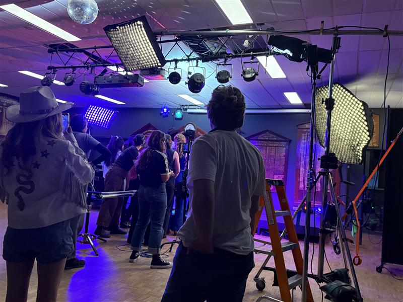 The rear of audience members in a studio with purple lighting