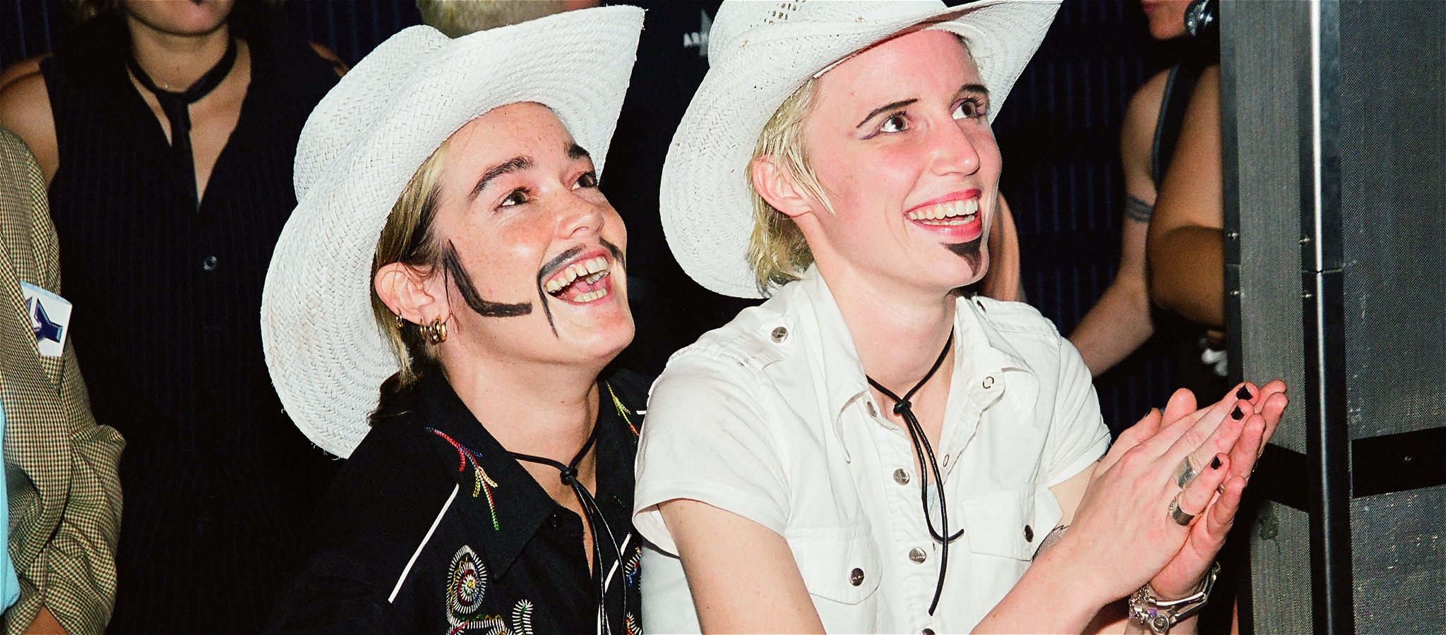 Two people wearing cowboy hats and drawn-on facial hair