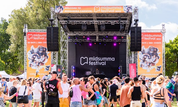 Midsumma Carnival Main stage with orange banners at the sides and a large crowd in the foreground