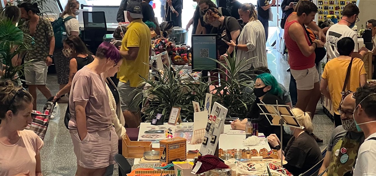 People perusing tables filled with goodies from queer makers and creators in the Victoria Pride Centre.