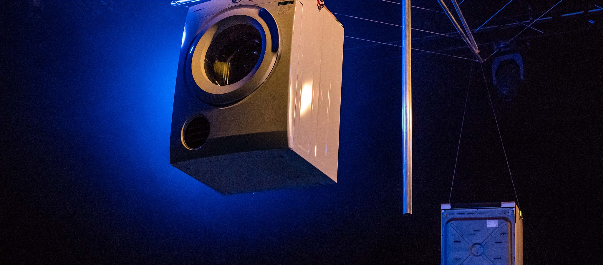 A large speaker hanging from the ceiling against a blue/black background