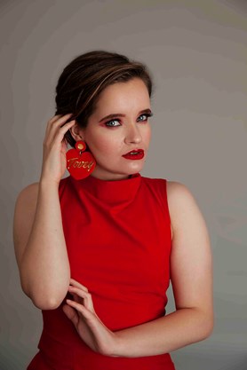 Person in a red dress, with a large red earring and bright red lipstick