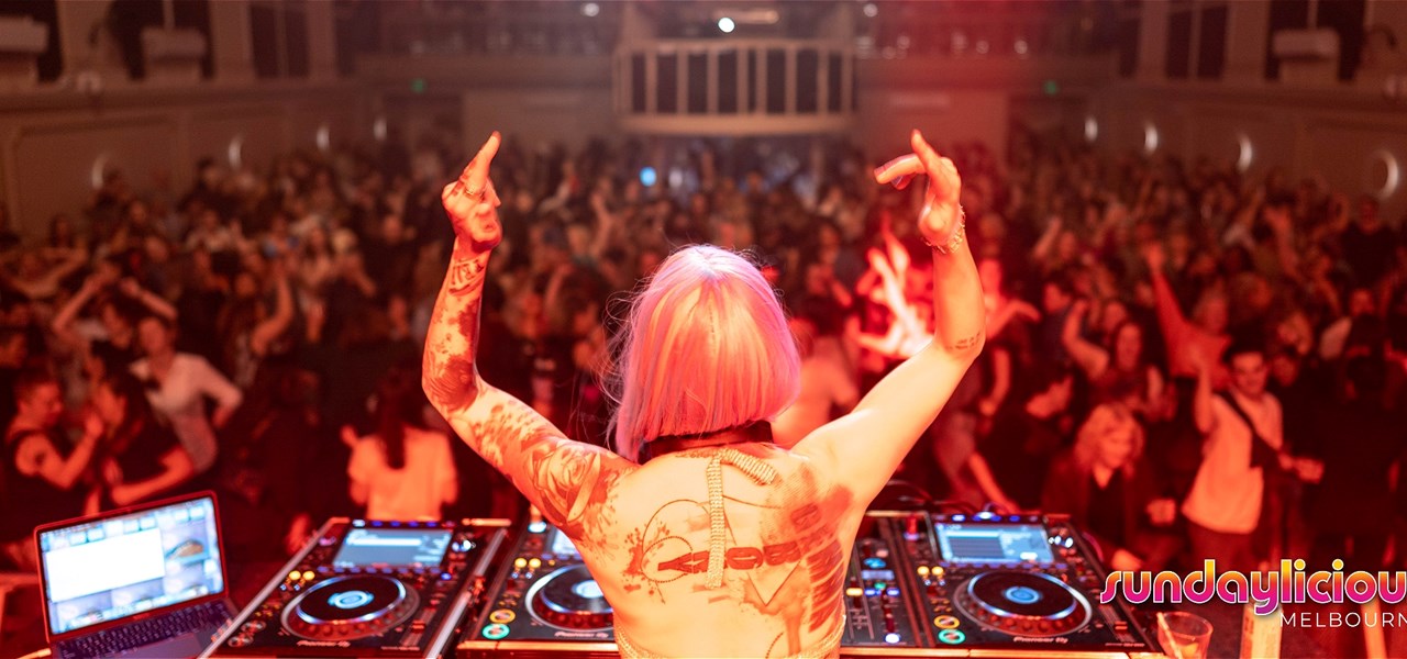 a DJ facing a large Sundaylicious dancing crowd