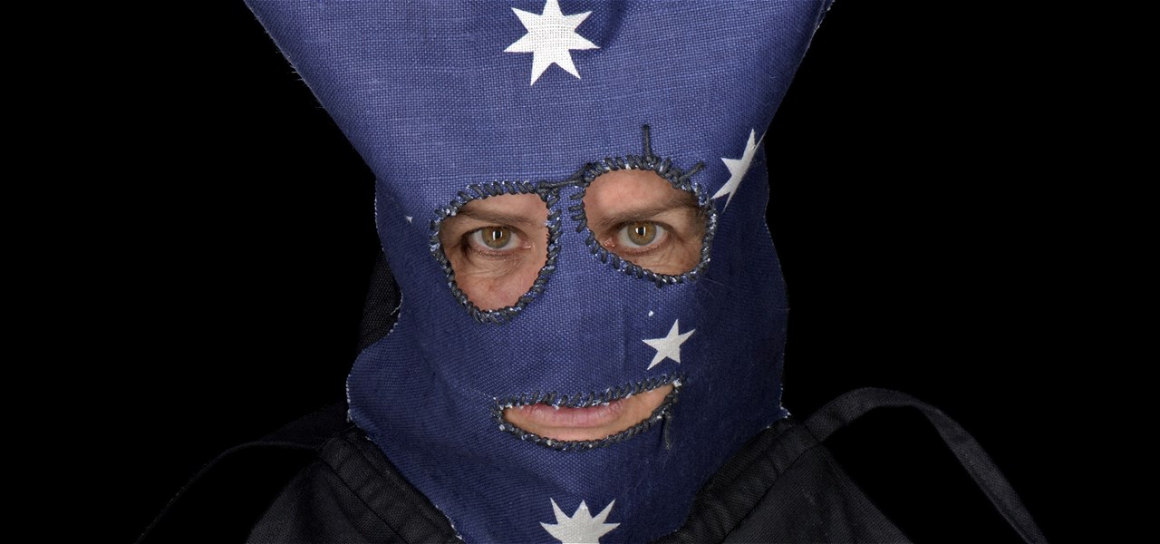 Headshot of a person wearing a blue denim headdress as a mask, with only the eyes and bottom lip visible.