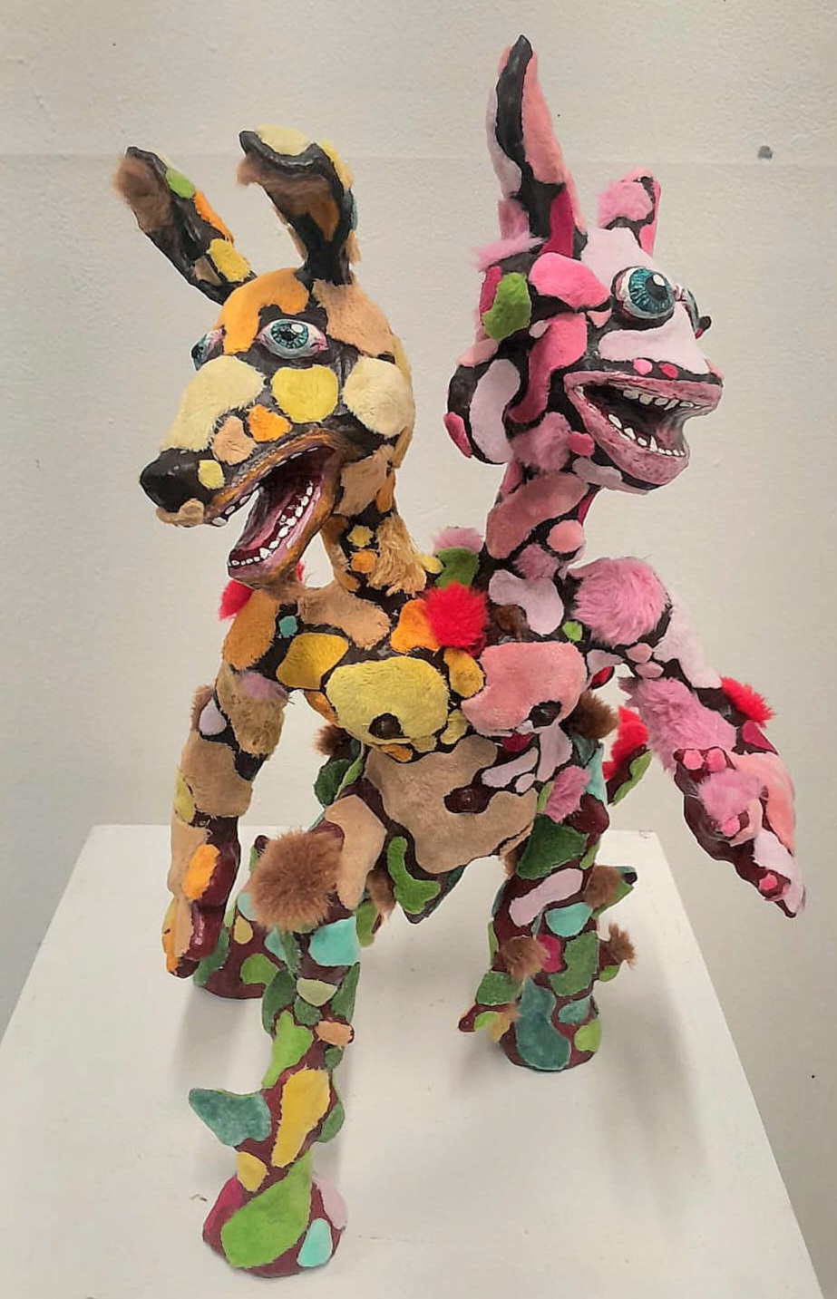 Lavishly decorated human-like object made from multi-coloured fabric with two animal heads