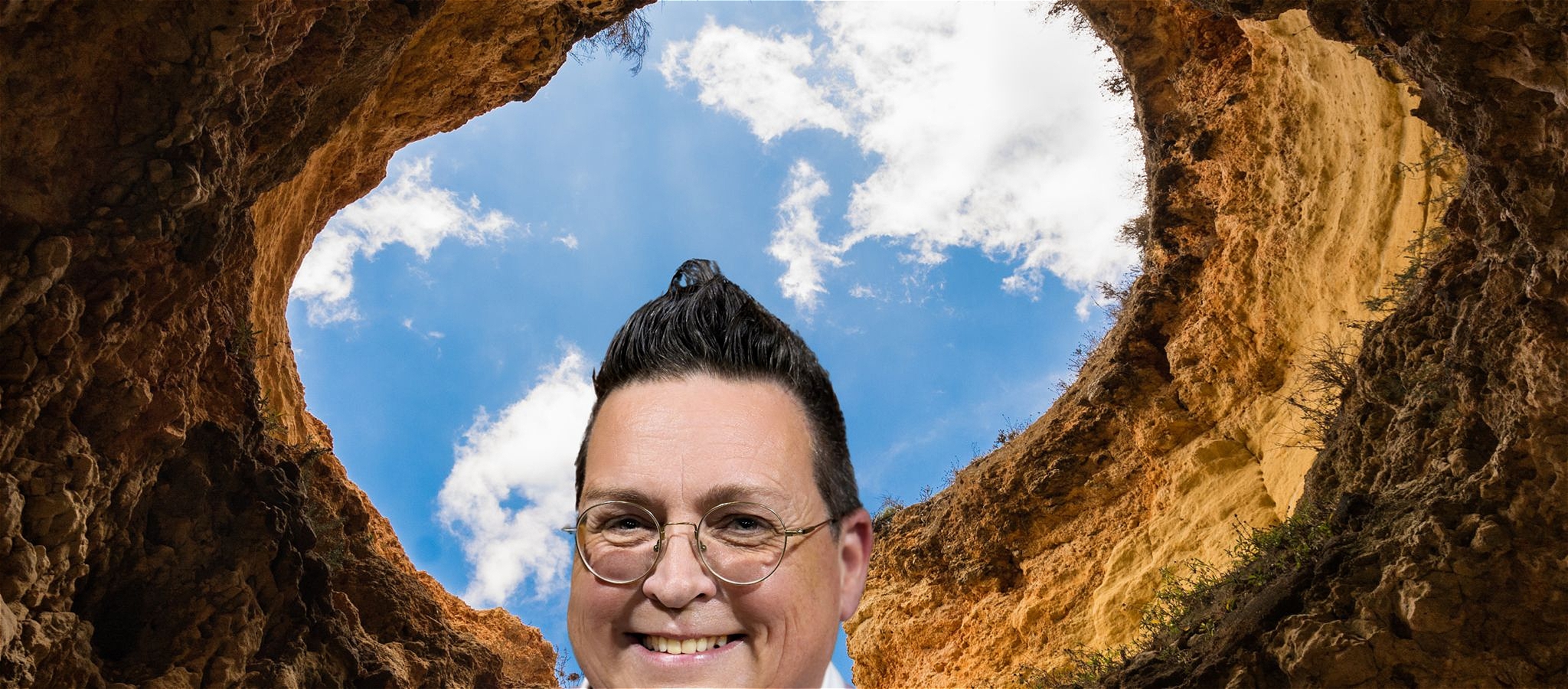 Jack's face looking over a hole dug in the ground with a blue sky behind.