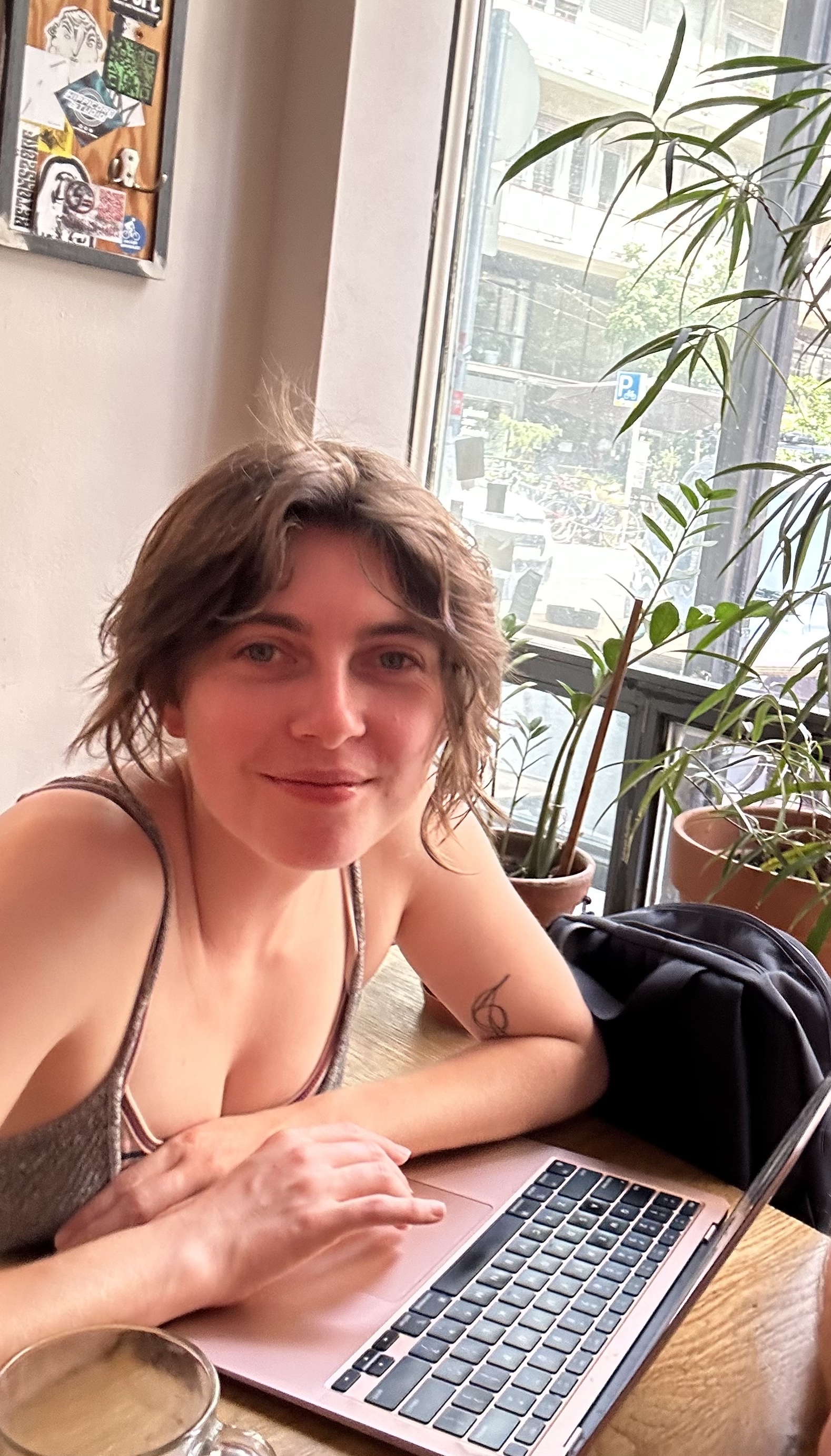 A person with brown hair wearing a tank top  smiling.