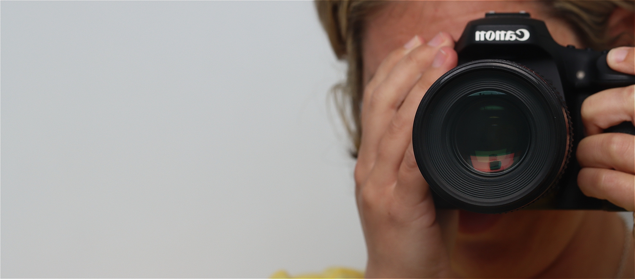 Photo of a photographer hidden behind their camera as they take a photo