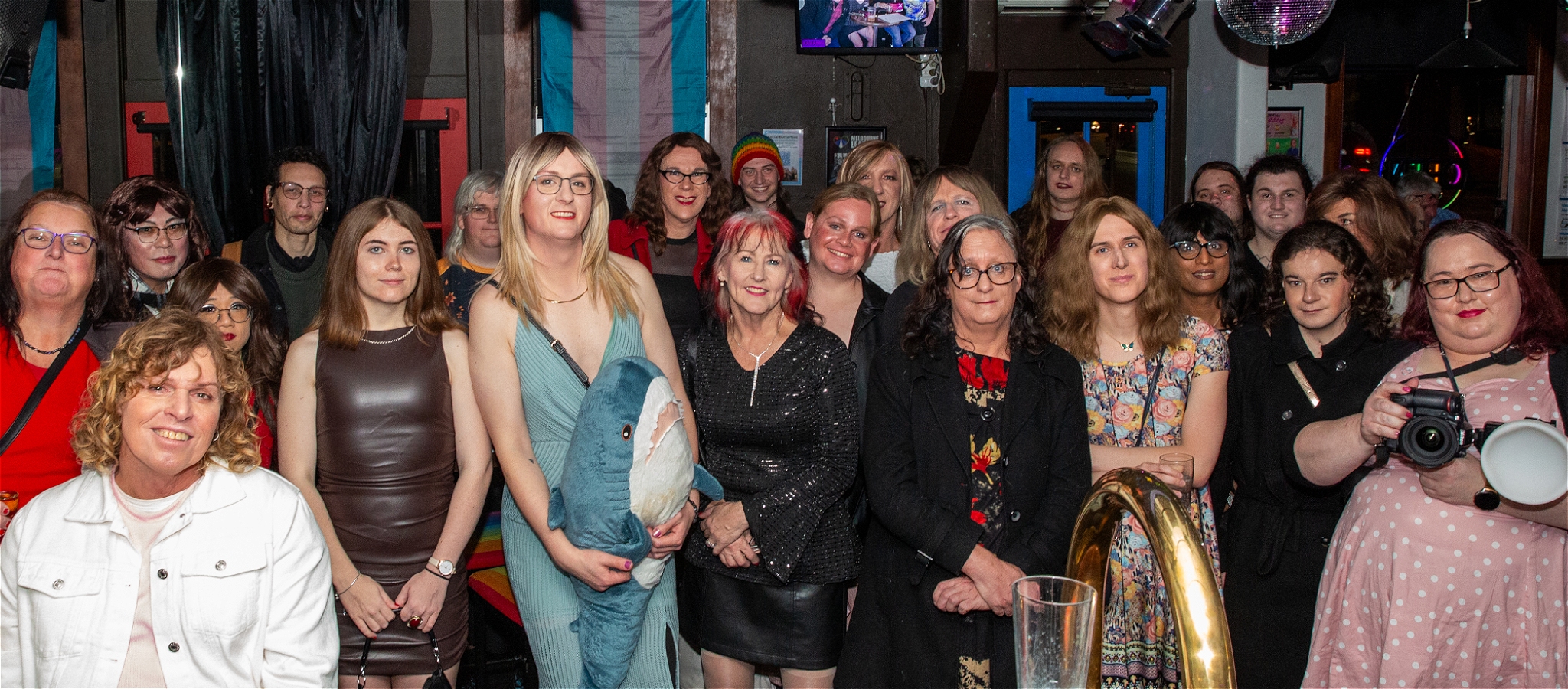 A crowd of trans femme and gender diverse people gathered for a group photo at a Social Butterflies event.
