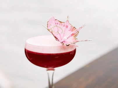 Glass of pink cocktail, with a pink umbrella in it