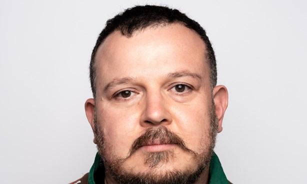 Ara Dolatian Headshot wearing a shirt that's green on one side and with multi-coloured stripes on the other