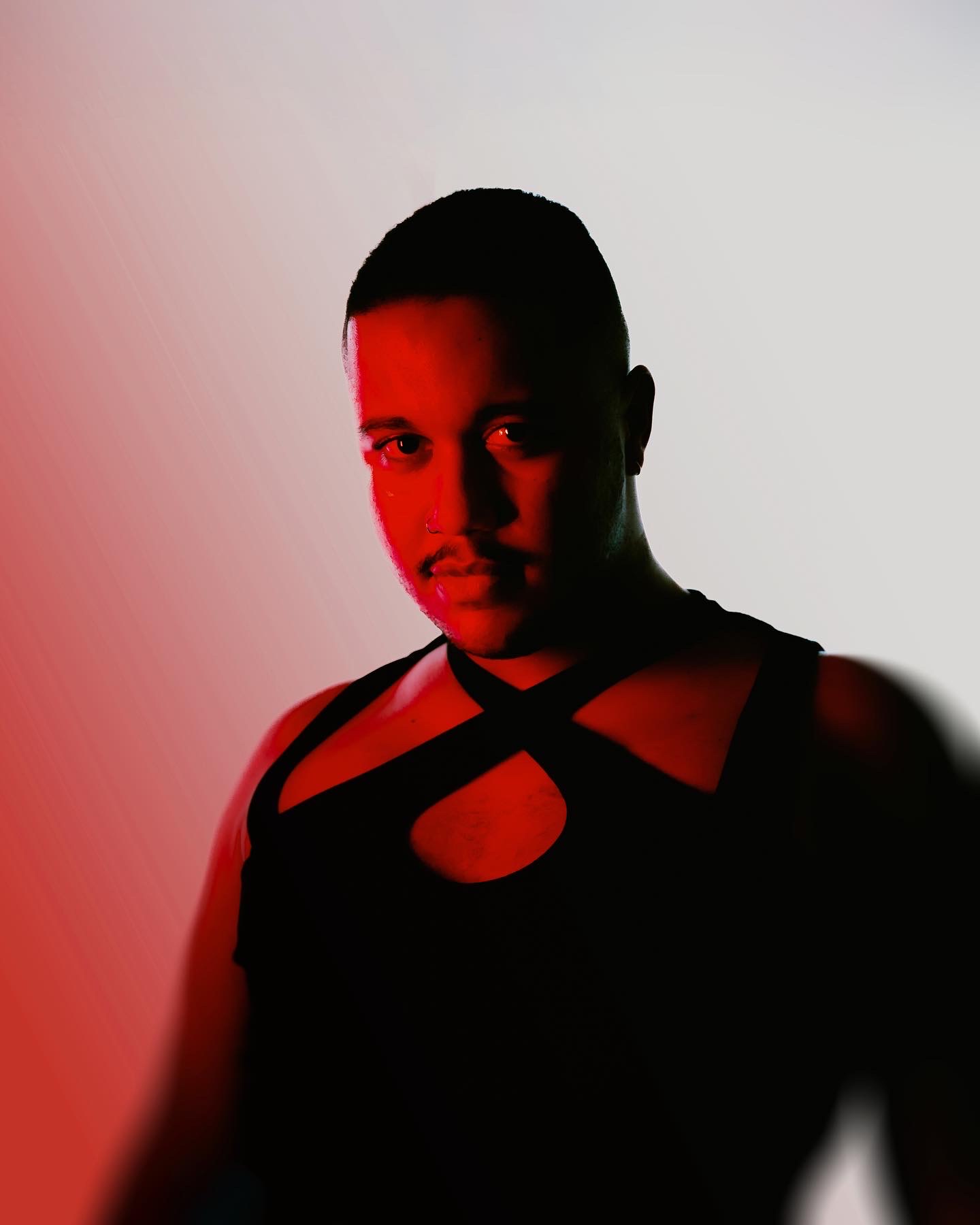 Headshot of Tavonga dressed in black against a red background