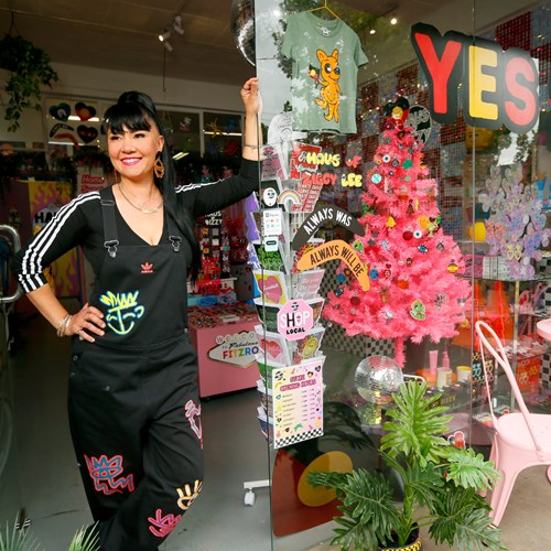 Person standing beside a stand in the store smiling broadly