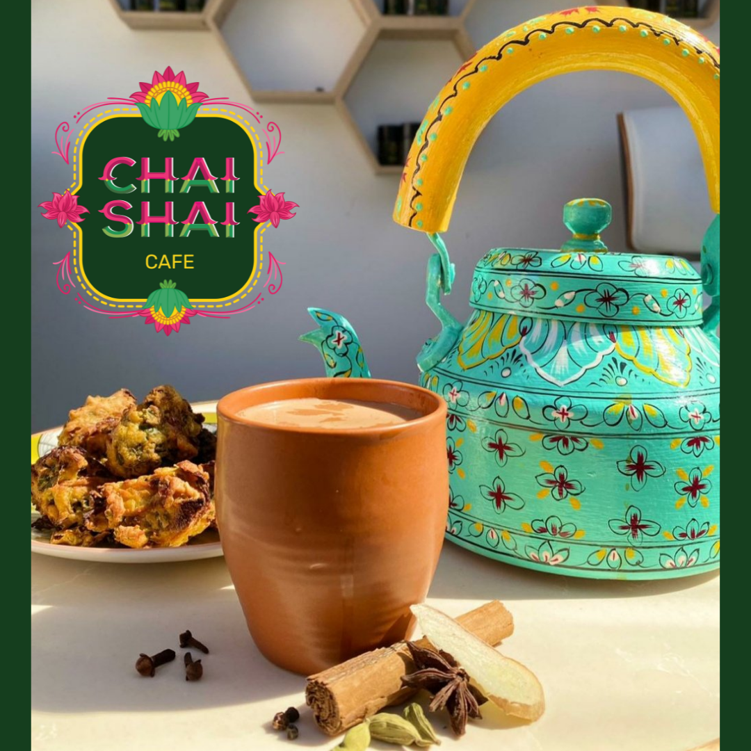 Teapot, tea cup and cake with 'Chai Shai Cafe text'.