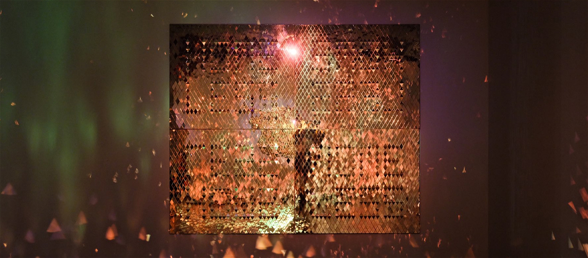 A still image of flames laps across triangulated, hand-cut glass to create a brilliant refraction of light within a darkened room
