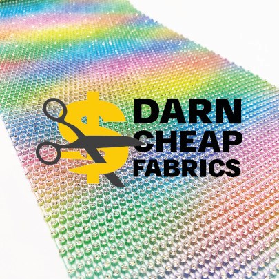 Rainbow fabric with text "DARN CHEAP FABRICS", a pair of scissors and a $ sign