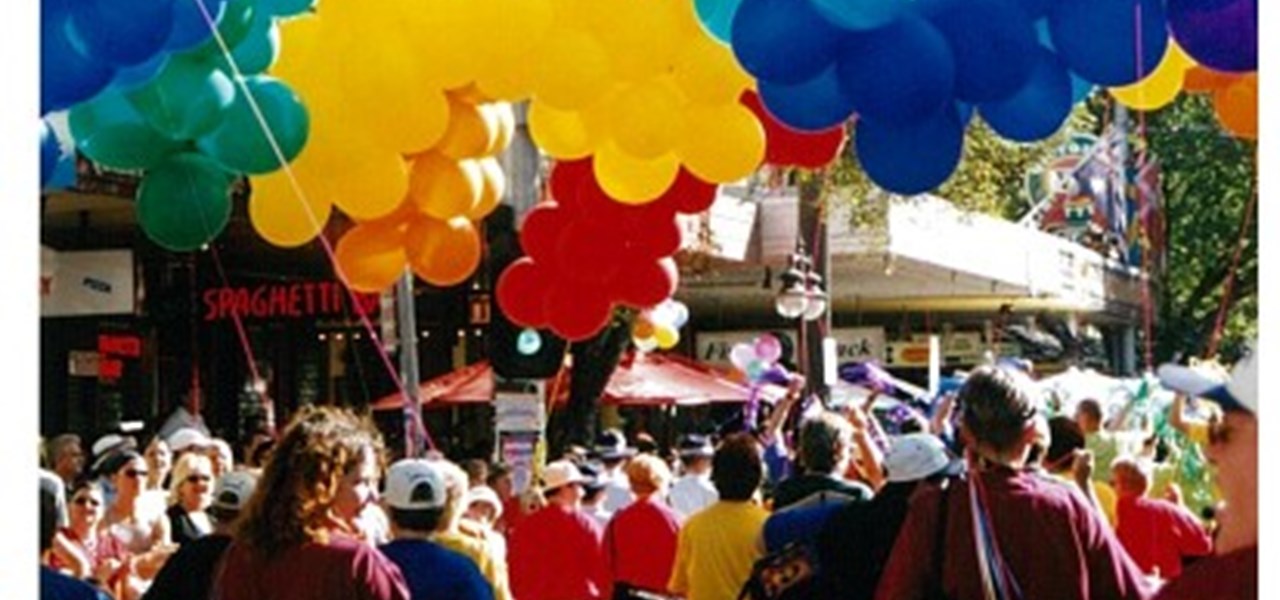 Pride March 2000 image: marchers under a cloud of coloured balloons, arranged in a pattern