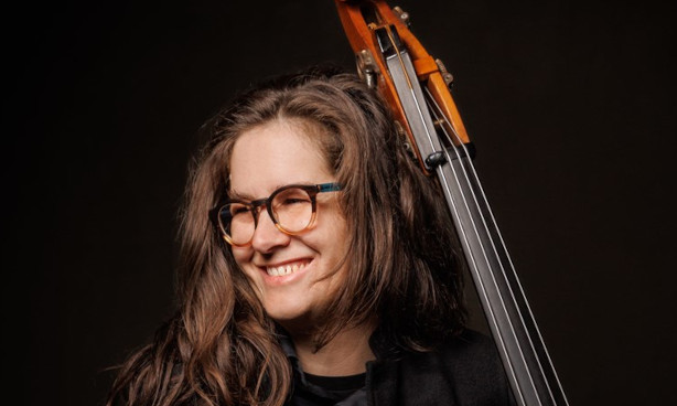 Miranda Hill smiling broadly while holding a double bass