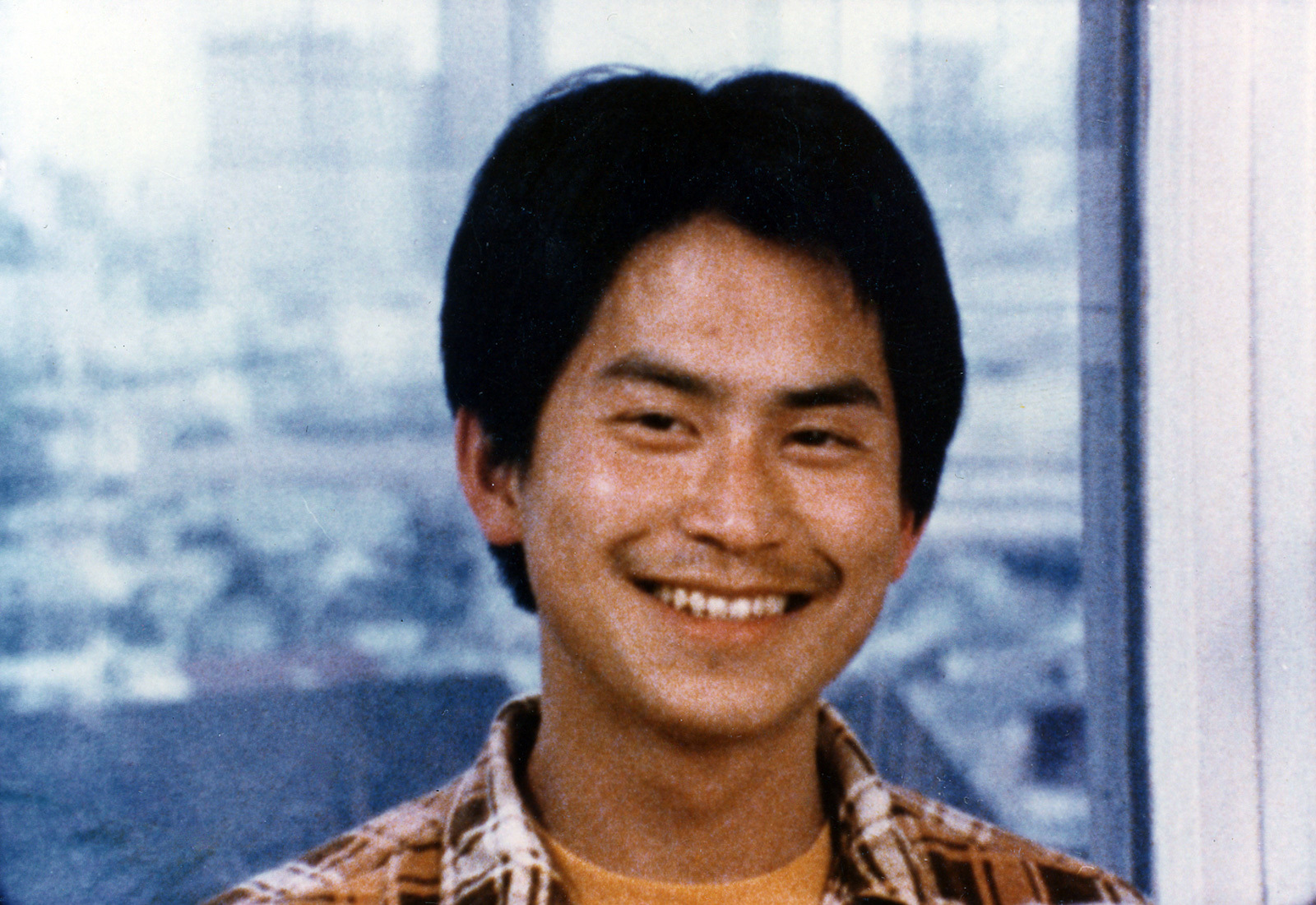 Grainy film of an Asian male smiling at the camera