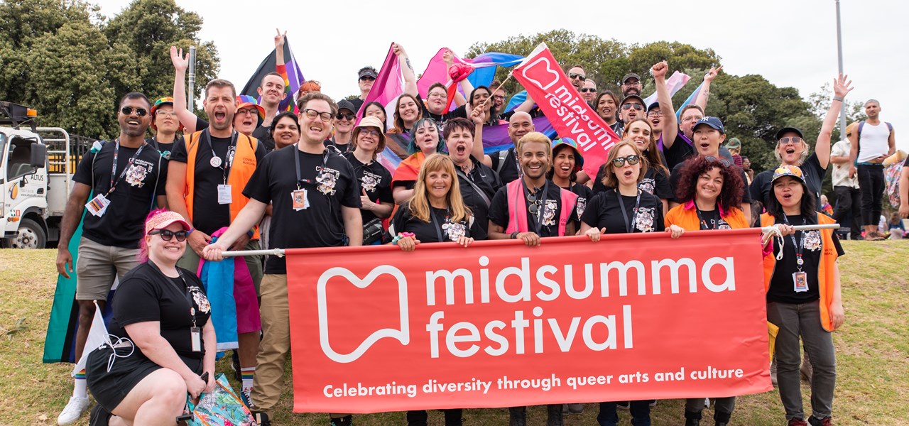 Midsumma staff and volunteers standing behind the Midsumma banner at Pride March 2023