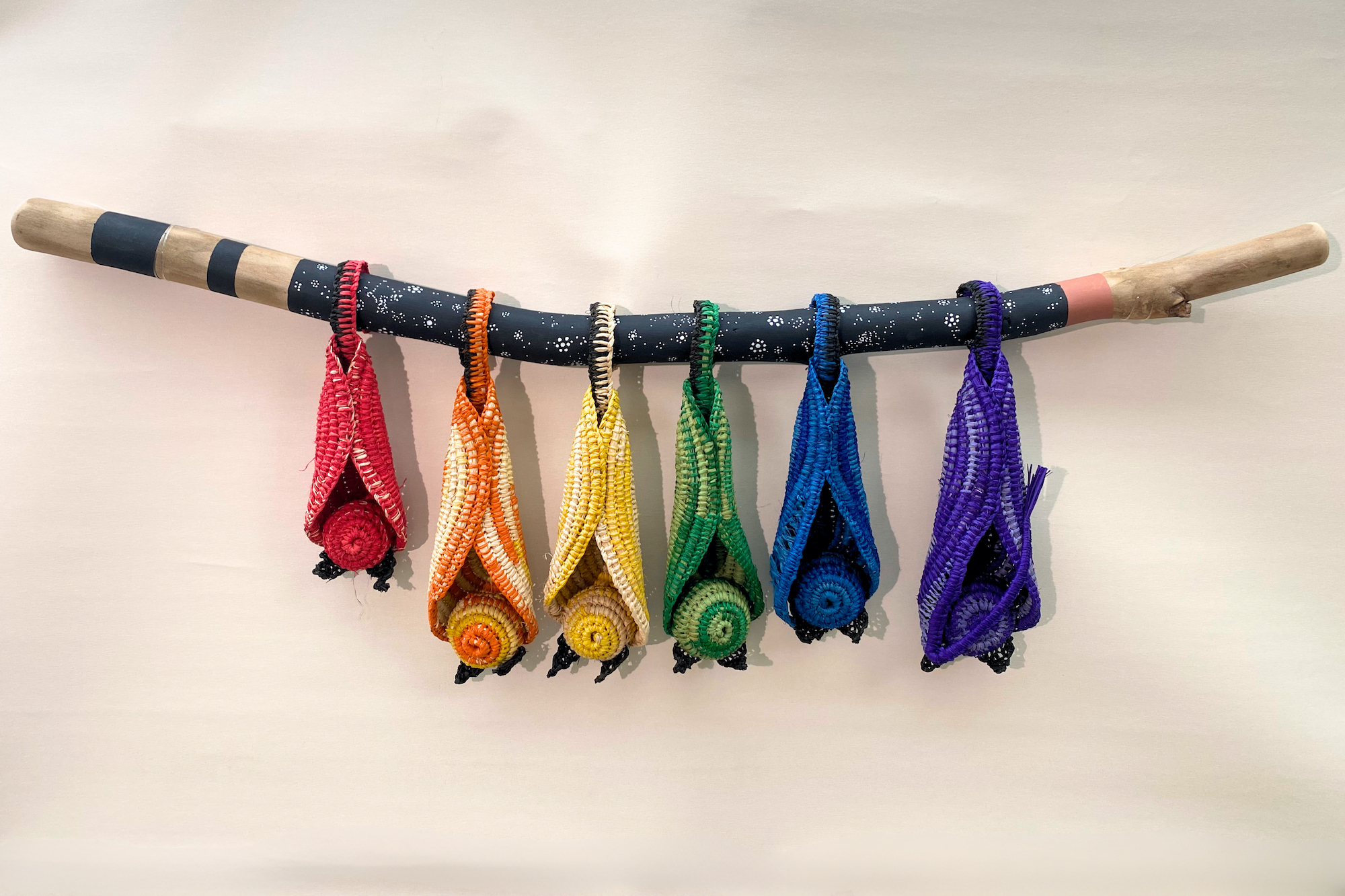 Coloured knitted bat-like figures attached to a wooden stick