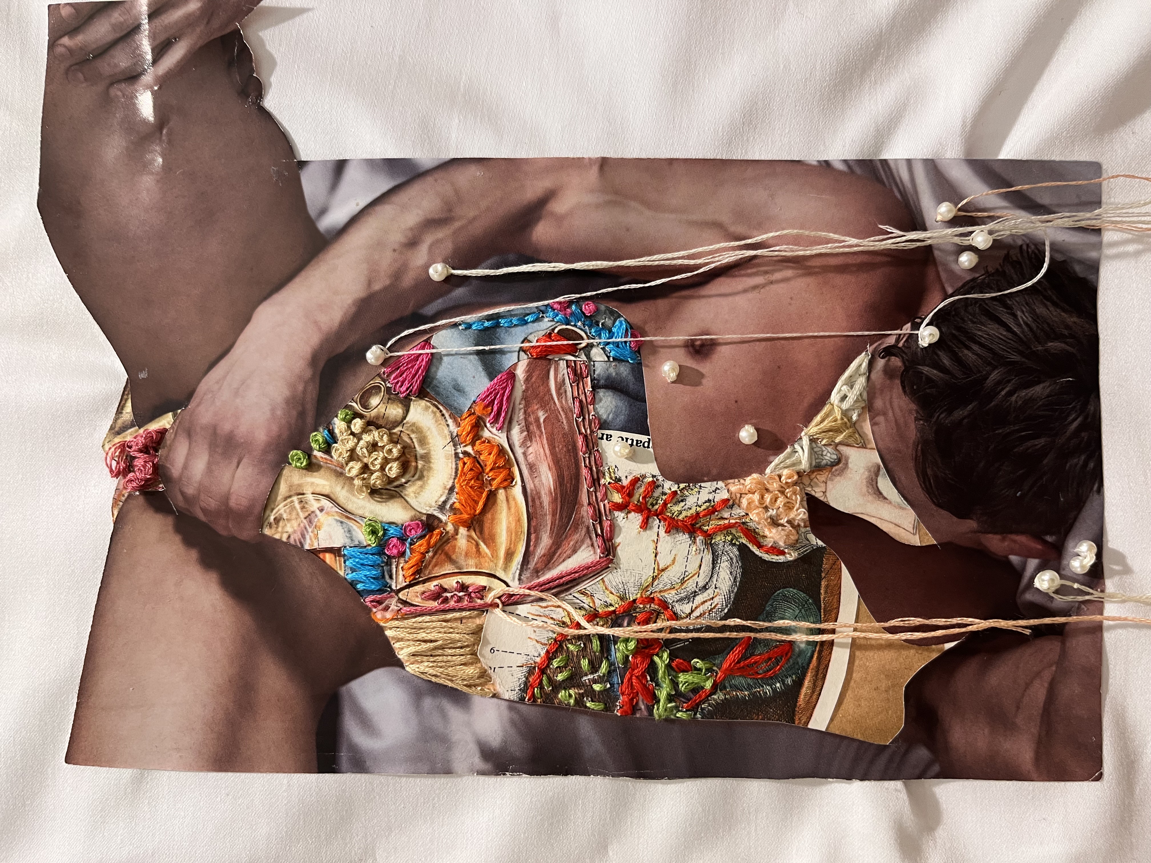 A naked person lying on a bed with a collage of fabrics laid over them