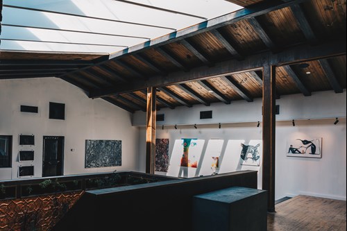 A light and airy gallery, with white walls, skylights and wooden rafters.