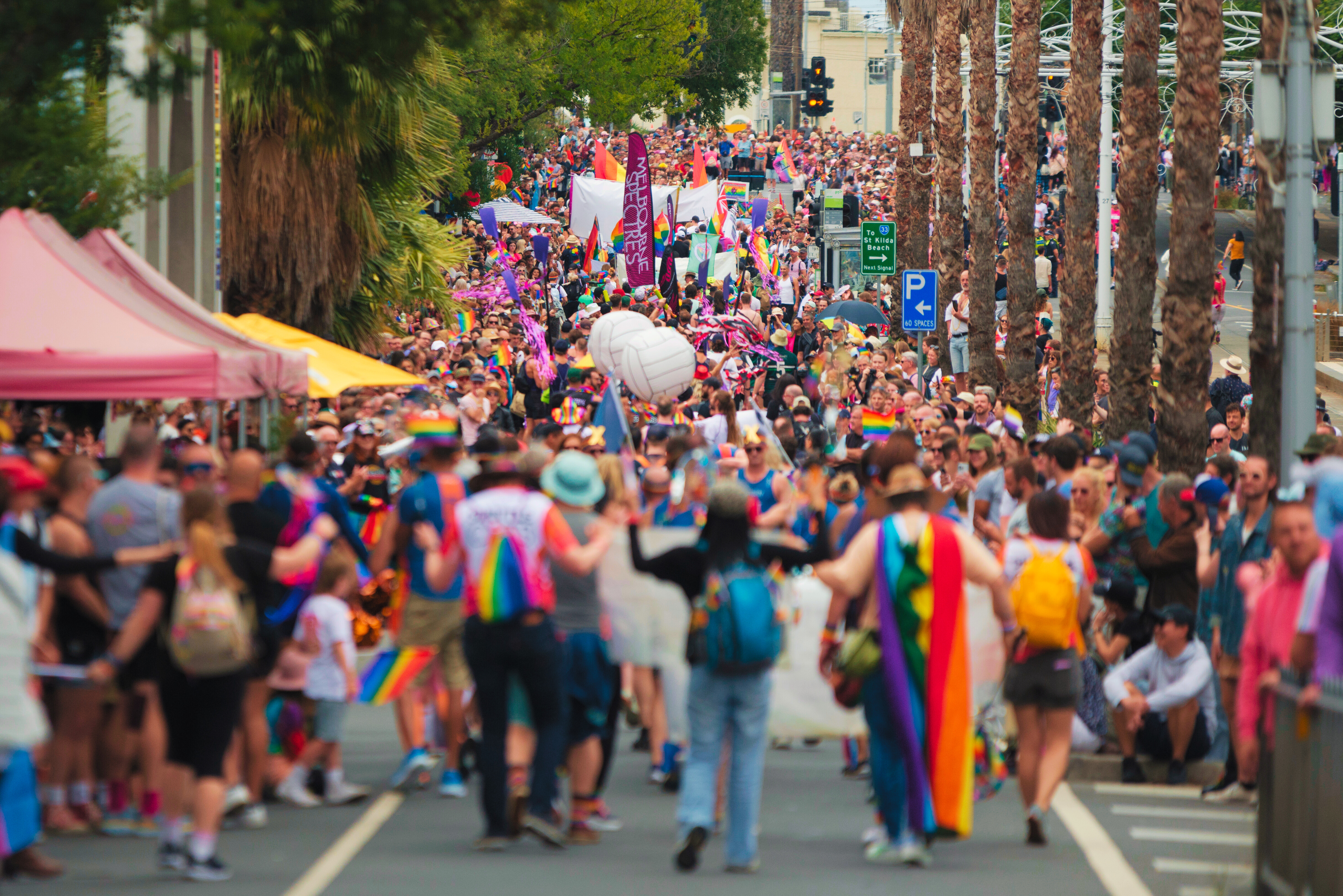 A large colourful procession of people marching down Fitzroy Street