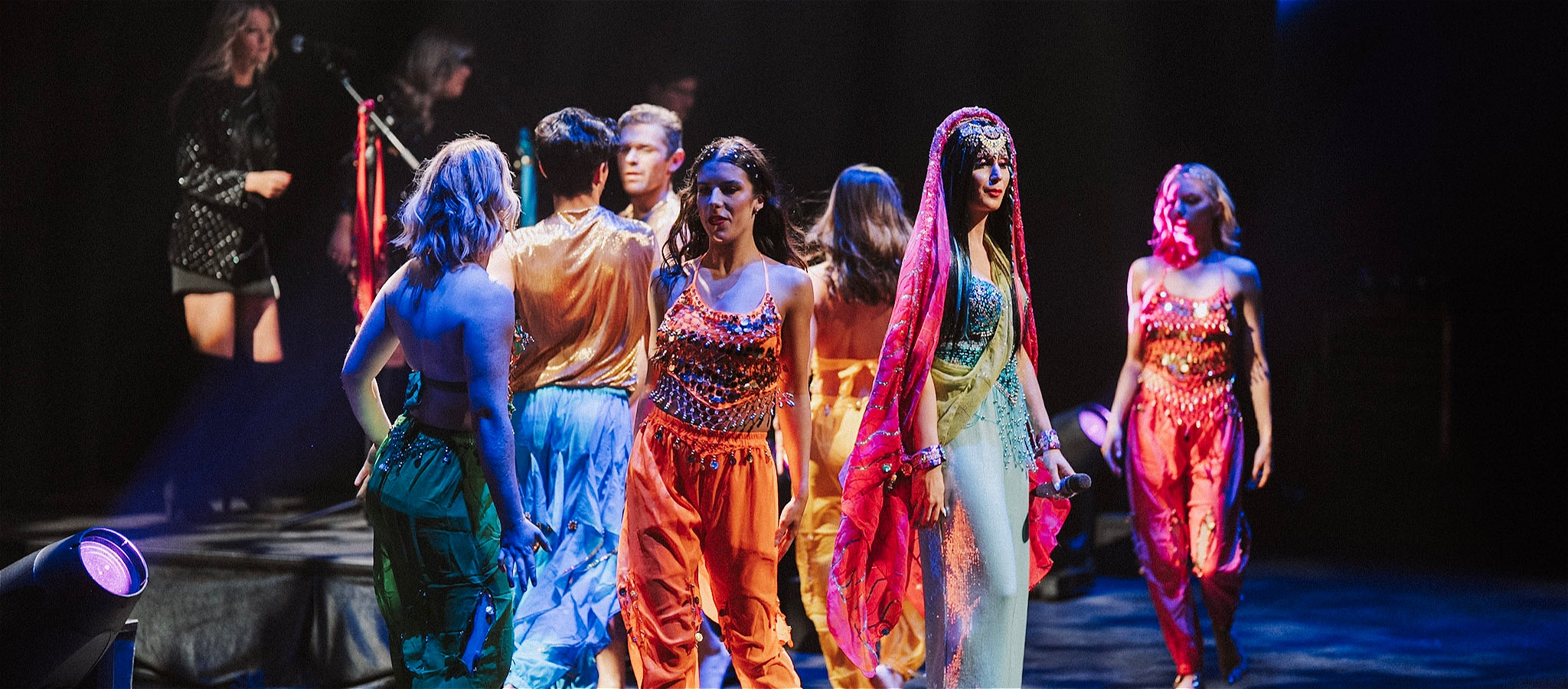 Singer and dancers on stage dressed in colourful costumes