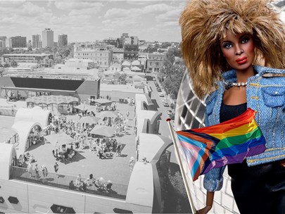 Doll of the singer Tina Turner holding a Pride flag in front of the Victorian Pride Centre roof and a giant mirrorball.