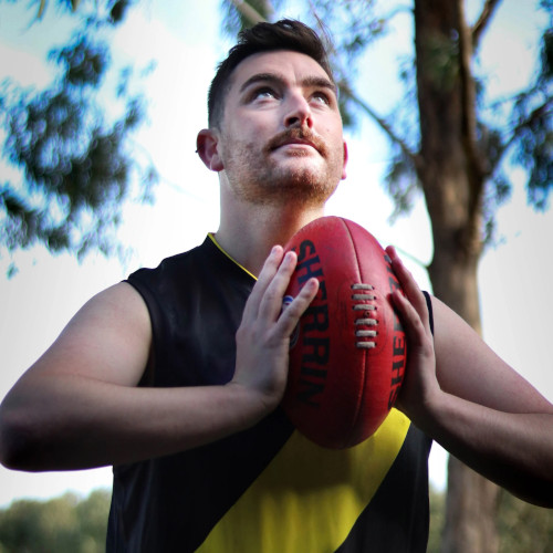 Samuel Roberts dressed as a footballer and holding a football while looking skywards