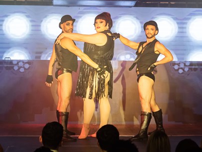 Three scantily dressed people on stage looking very burlesque-like