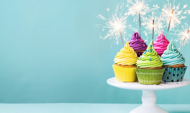 Cupcakes on a raised plate, with sparkling candles and an aqua background