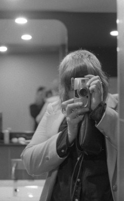 Black and white photo of Emma pointing their camera at the photographer