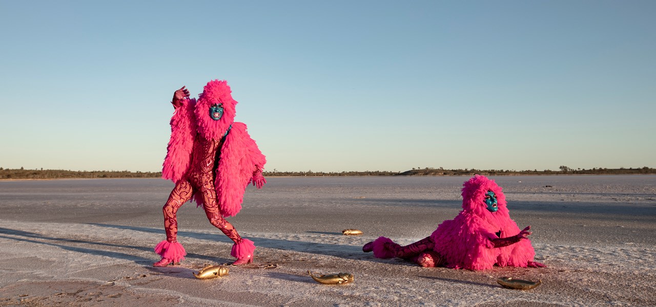 The Huxleys in pink feathery outfits on a salt lake