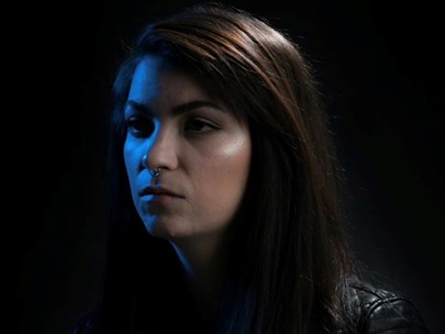 Side profile of Sarah-Jayde. The filter on the photo makes everything look dark and moody. Sarah-Jayde has a septum ring, black leather jacket and is not smiling.