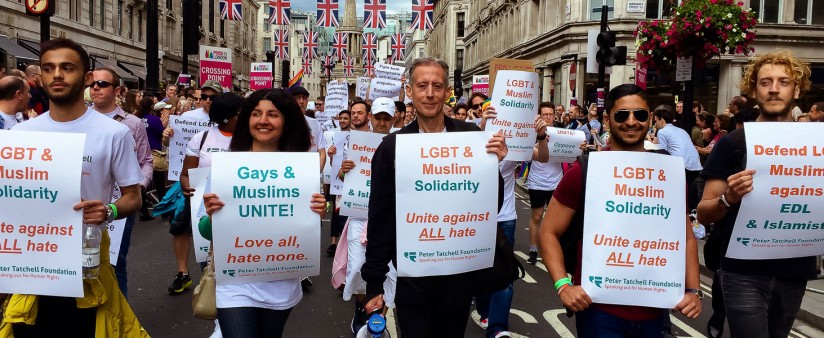 A street protest with lots of people holding signs about gays and muslims against hate