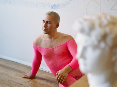 Jonathan Homsey sitting on the floor while wearing a pink see-through one-piece