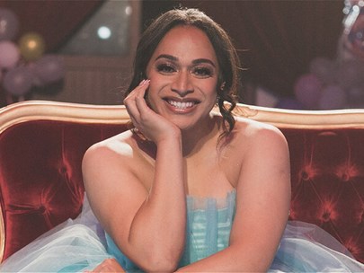 A person wearing a blue dress sitting on a red chair.