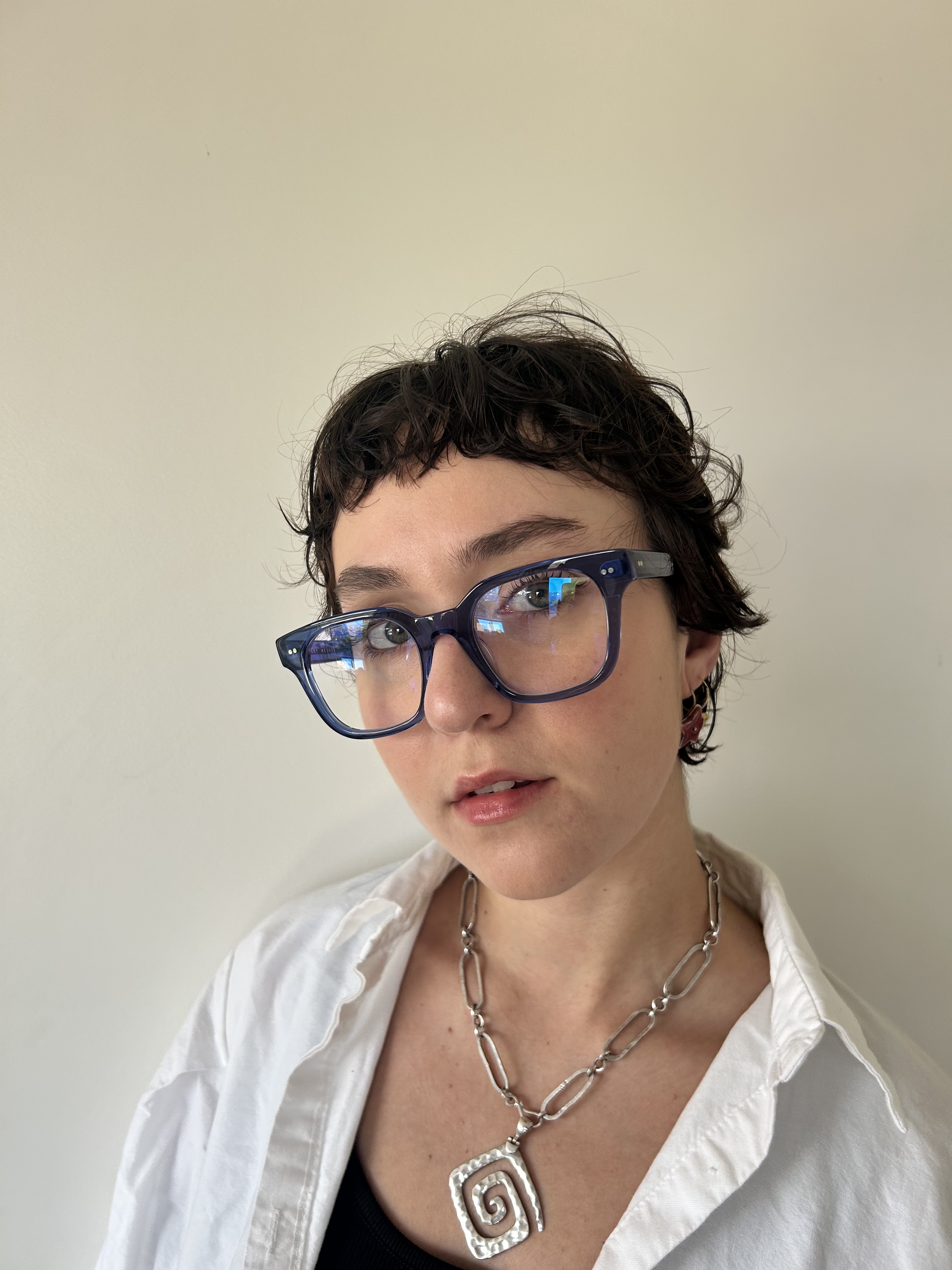 A person with brown hair wearing blue glasses.