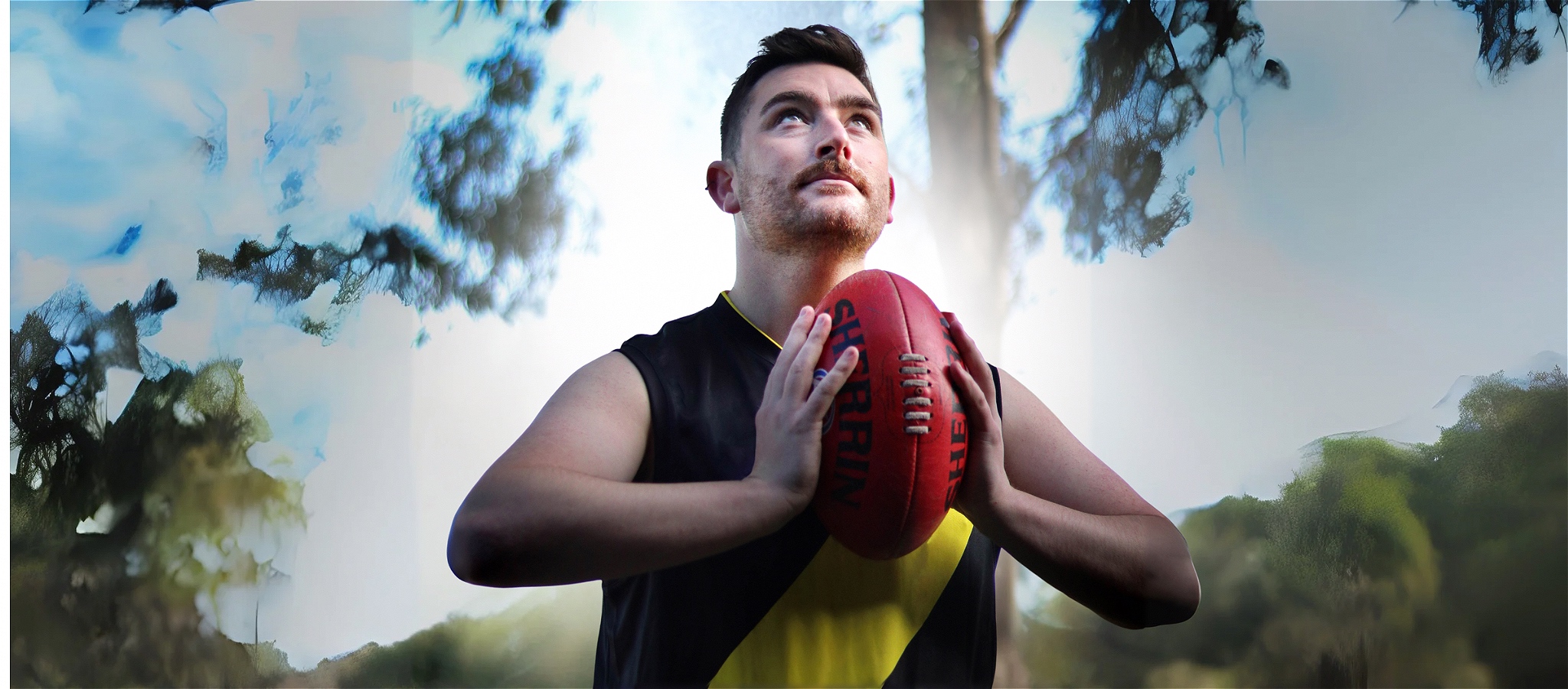 A person in black and yellow football attire and white high heels, sitting on a fence holding a red football.