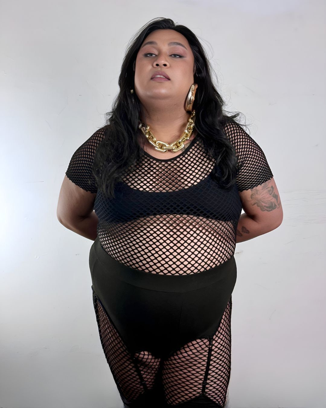 Dax Carnay wearing black lace with arms behind their back
