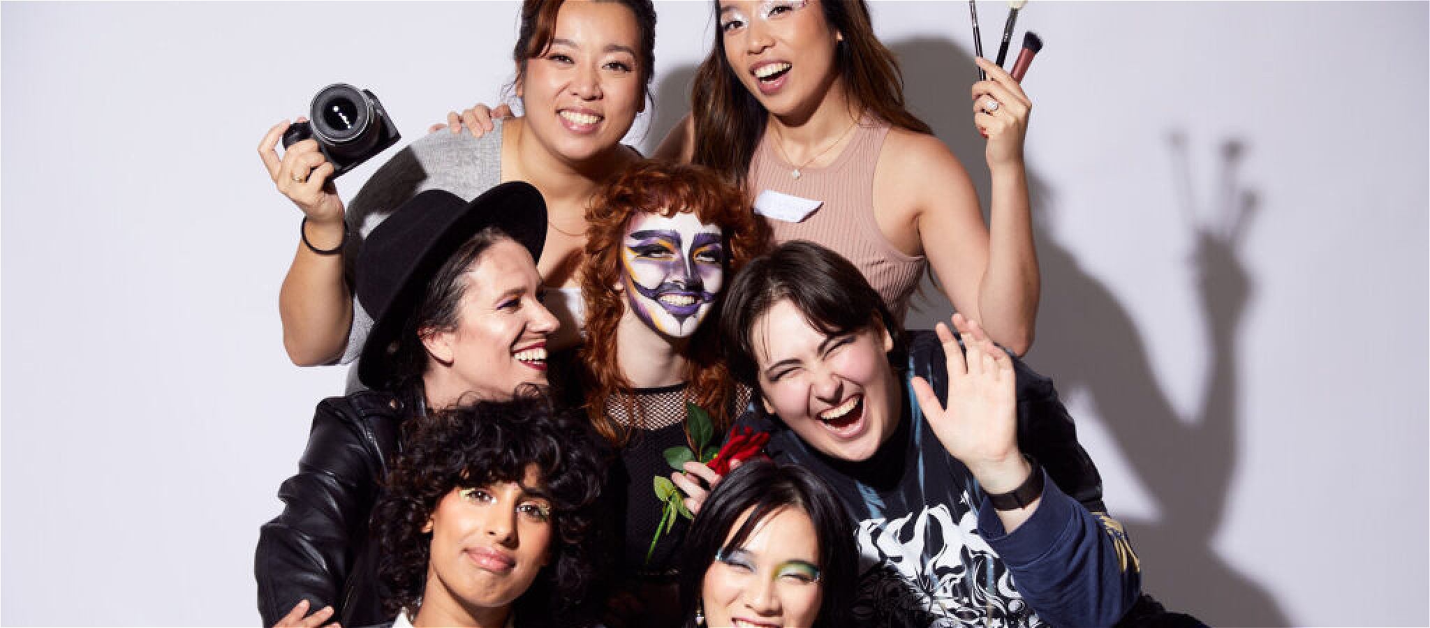 Group of 7 smiling people with unique makeup