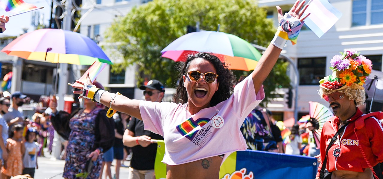 A colourfully dressed person with their arm in the air at Midsumma Pride March